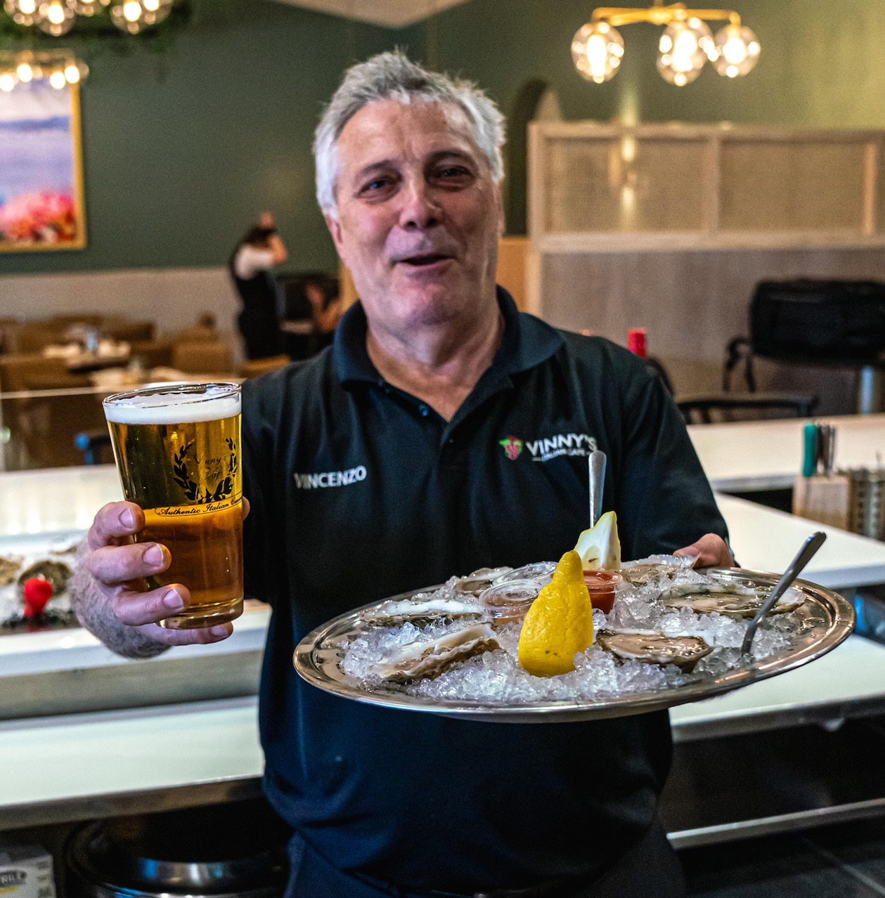 Vincenzo, a Vinny's server, with a cold beer and a tray of fresh oysters